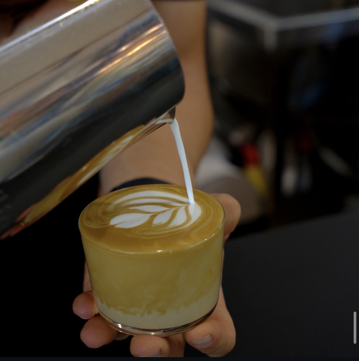Pouring latte art into a glass cup