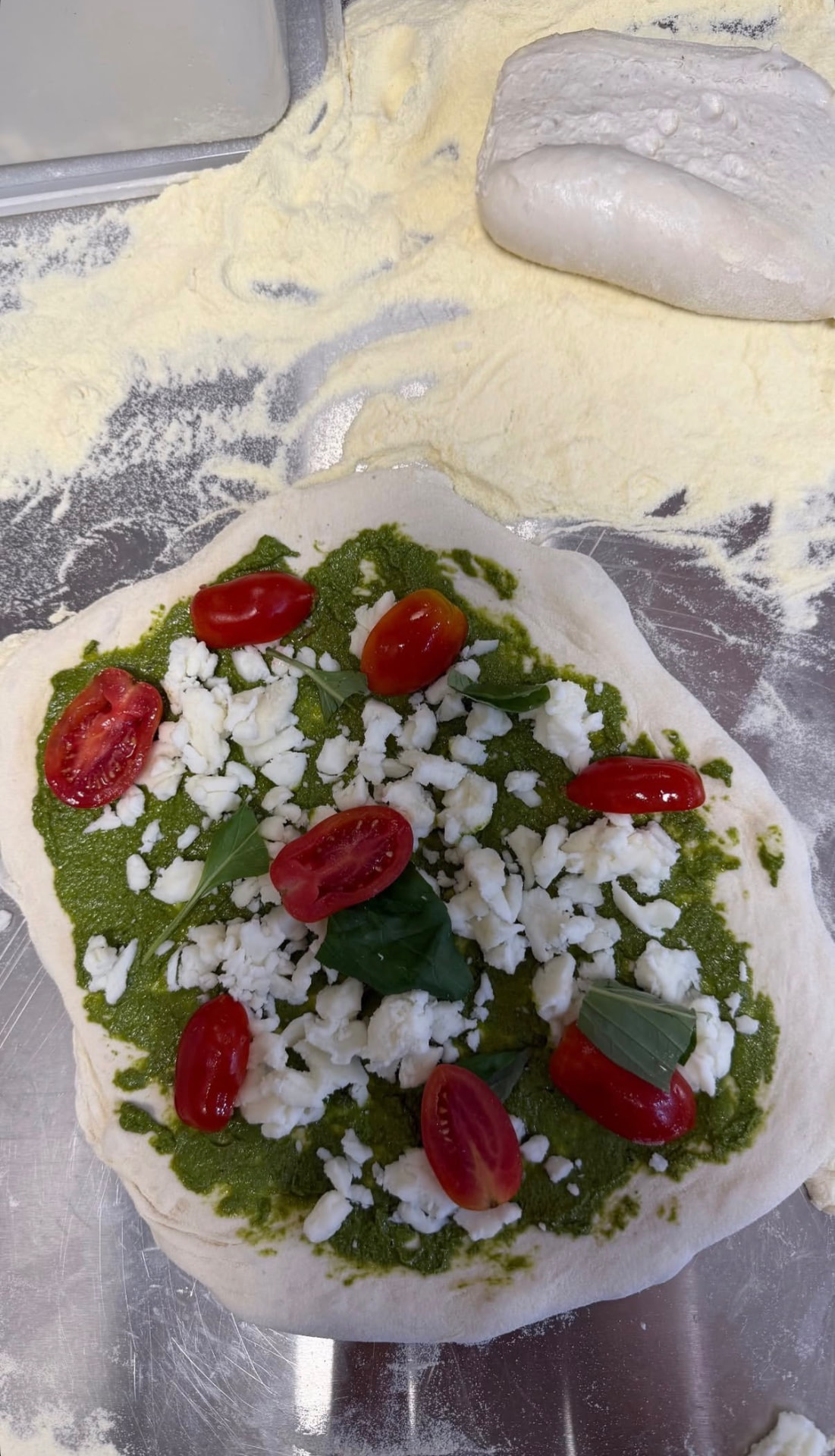 Pesto, feta and cherry tomato pizza before baking