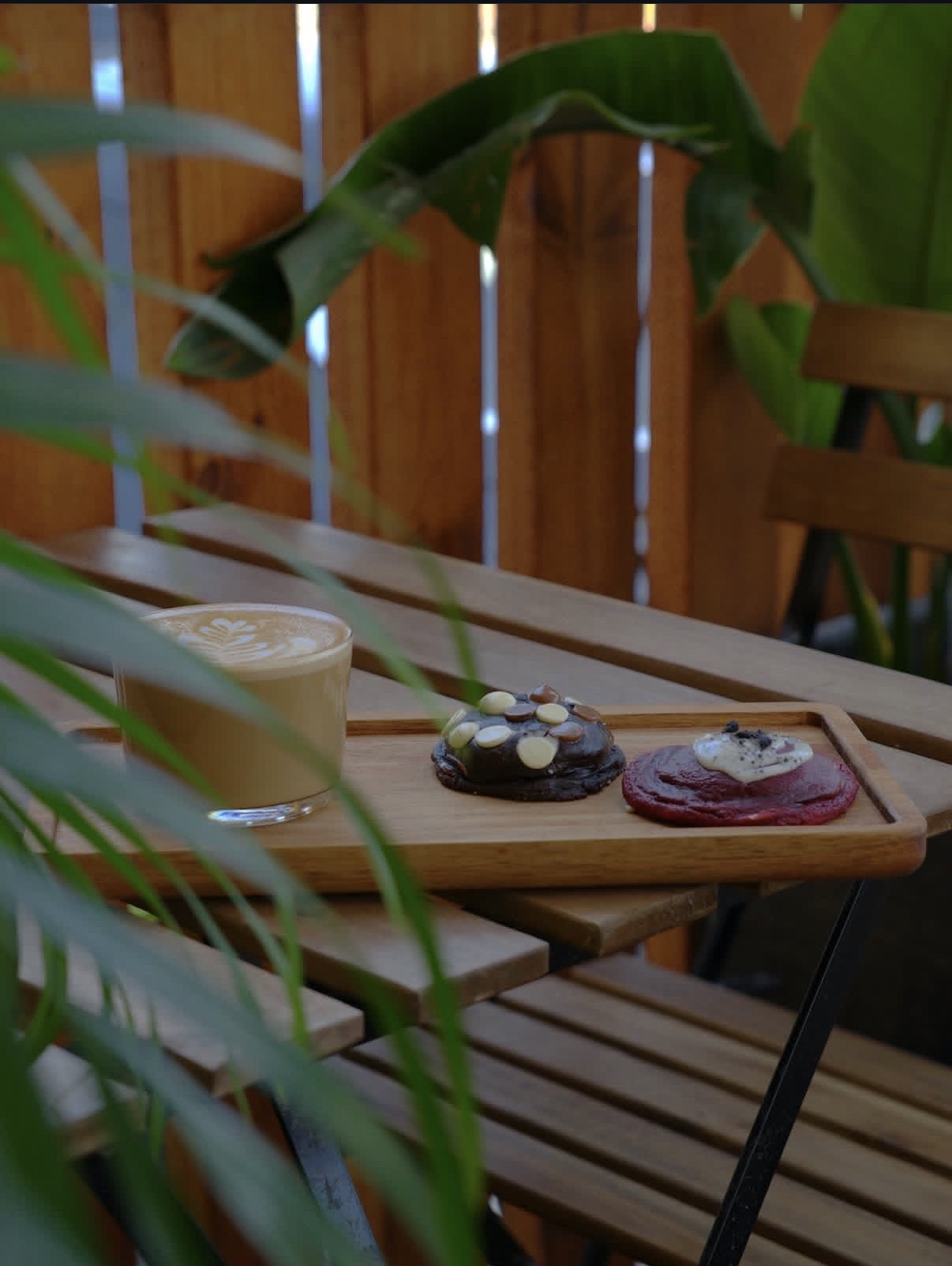Latte with chocolate and red velvet cookies on a wooden tray