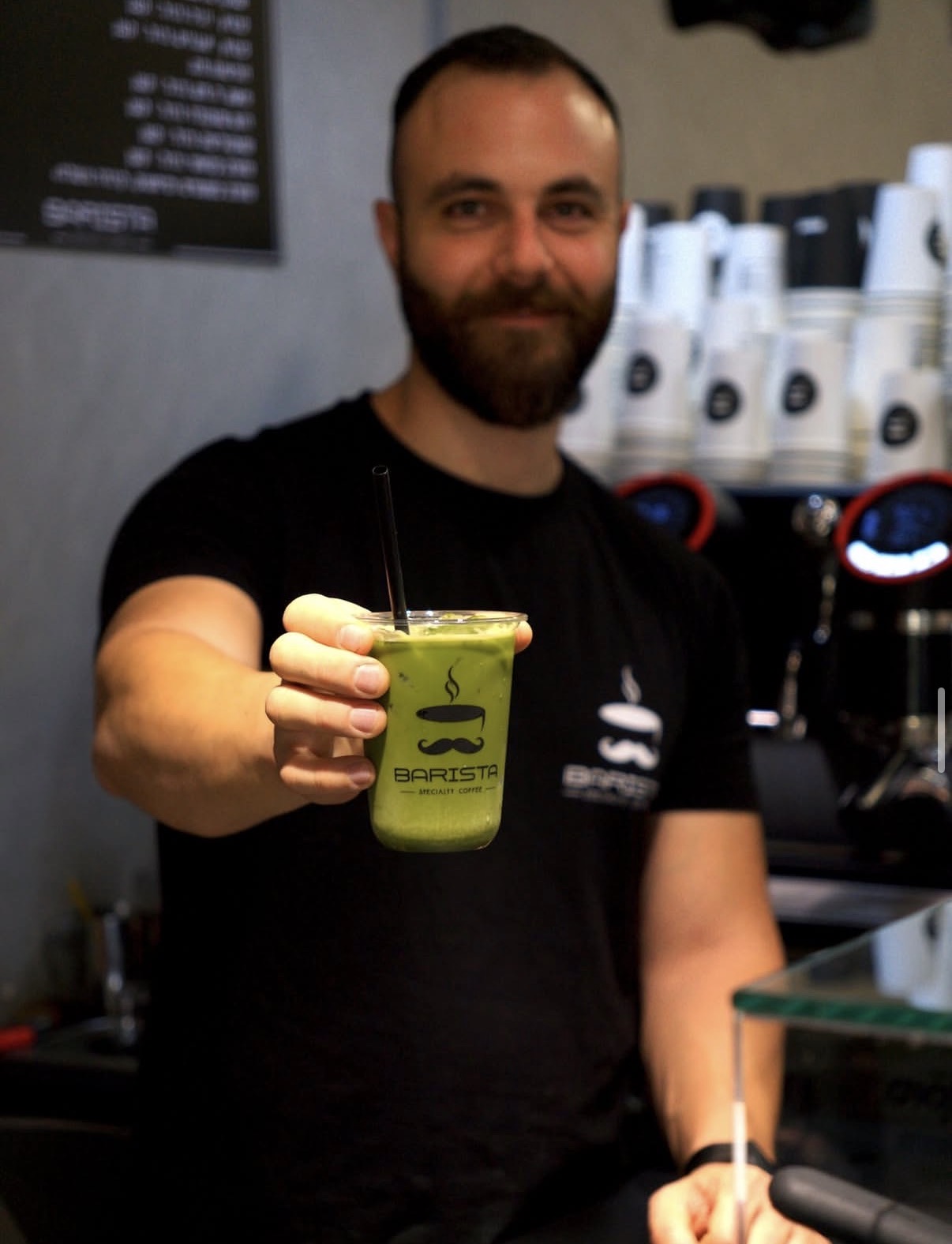 Barista holding an iced matcha latte at the counter